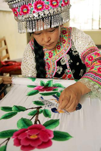 8月14日，一名彝族婦女展示彝族傳統刺繡工藝。