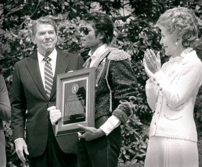 During a May 1984 ceremony at the White House, Michael Jackson accepts a Presidential Award from President Reagan as first lady Nancy Reagan looks on. Jackson was honored as a model for American youth, and for lending his hit song "Beat It" to a new campaign against drunk driving.