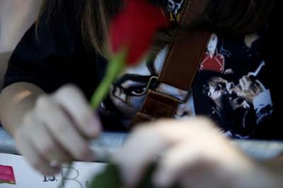 A fan wearing a Michael Jackson t-shirt holds a rose by a memorial for the deceased pop star outside the Jackson family home in Encino, California July 3, 2009.(Xinhua/Reuters Photo)