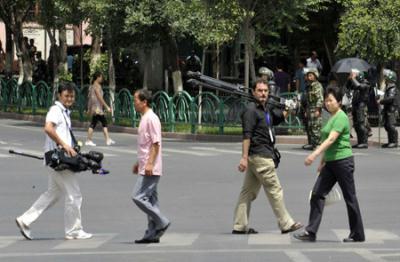 Overseas journalists carrying equipment walk on a street in Urumqi, capital of northwest China's Xinjiang Uygur Autonomous Region, July 8, 2009.  (Xinhua/Shen Qiao)