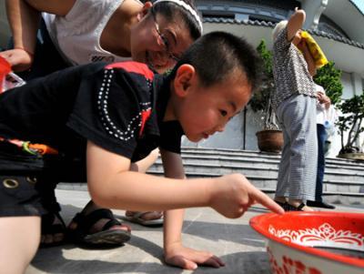 A child observes the sun eclipse through water reflection in Taiyuan, capital of China's Shanxi Province, on July 22, 2009.(Xinhua Photo)