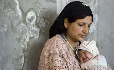 An Afghan woman carries her child at a wool workshop in Herat, western Afghanistan August 18, 2009. [Agencies]