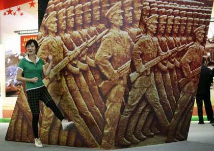A visitor poses for a photograph in front of a display of marching soldiers at an exhibition showcasing the achievements China has made in the past six decades, ahead of October's 60th anniversary of the founding of the People's Republic of China, in Beijing September 21, 2009. [Agencies]