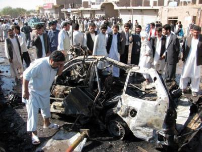 Afghan bystanders look at the wreckage of a destroyed car at the site of an explosion in Herat city, Sept. 27, 2009. A roadside bomb targeting an Afghan cabinet minister exploded in the western city of Herat on Sunday, killing at least four civilians and wounded 17 others, but the official escaped unhurt, sources said.(Xinhua/AFP Photo)