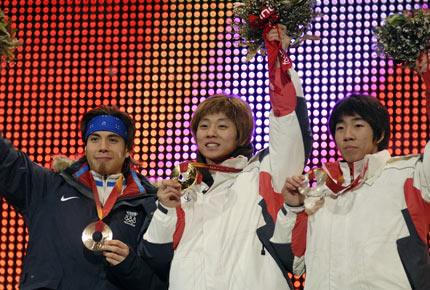 Turin, Medals Plaza, 19 February 2006, XX Olympic Winter Games. Medal ceremony for the men's 1000m short track speed skating: (L-R) American Apolo Anton OHNO and Koreans Hyun-Soo AHN and Ho-Suk LEE wave to the audience. Credit: IOC/Richard Juilliart