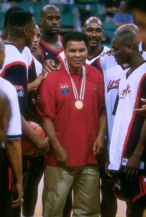 Atlanta, 3 August 1996. Games of the XXVI Olympiad: the American basketball team gather around former boxing champion Muhammad ALI, who is carrying the gold medal which he won at the Rome Olympic Games in 1960 and had lost in the interim. Credit: Getty Images/Doug Pensinger