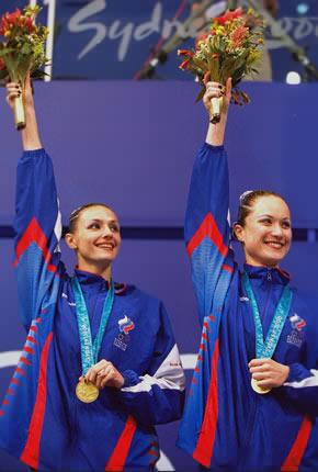 Sydney, 26 September 2000, Games of the XXVII Olympiad. Synchronized swimming: Olga BRUSNIKINA (L) and Maria KISSELEVA from Russia wave to the audience after receiving their gold medals for the duet competition. Credit: Getty Images/Ross Kinnaird