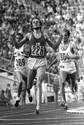 1972: Lasse VIREN (#228) of Finland raises his hands in victory at the conclusion of his gold medal win in the men's 5000m at Games of the XX Olympiad in Munich. Tunisian Mohamed GAMMOUDI, (#904) was second and Ian STEWART of Great Britain (#309) was third. Credit: Getty Images/Hulton Deutsch