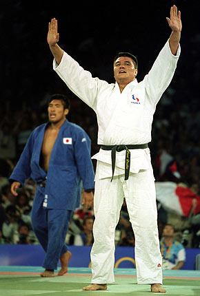 Sydney, 22 September 2000, Games of the XXVII Olympiad: David DOUILLET of France celebrates winning the gold medal in the men's heavyweight judo event. Shinichi SHINOHARA of Japan, in the background, claimed the silver medal. Credit: Getty Images/Robert Cianflone