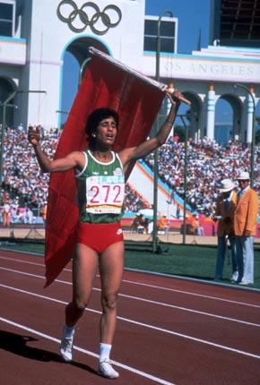 Los Angeles, 8 August 1984, Games of the XXIII Olympiad. Women's 400m hurdles winner, Nawal EL MOUTAWAKEL raises the Moroccan flag during her lap of honour in the Coliseum. Credit: Getty Images