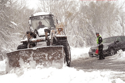 一輛鏟車在交警的指揮下正在清理路面積雪。昨天，延慶縣遭遇了52年來最大降雪。新華社發