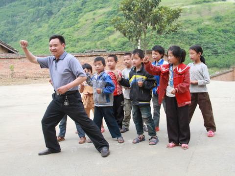 孩子們，就像我這樣做。陳良根在教孩子唱歌做手勢。