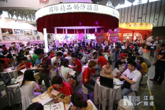 8月11日，在南京網友婚博會上，參觀者在一家婚慶服務企業的展臺諮詢。