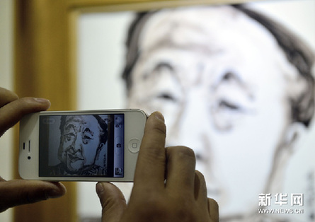 12月9日，一位觀眾拍攝羅皓的瓷板畫《作家莫言》。新華網圖片 于點 攝