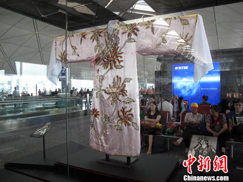 在香港國際機場候機室展出的一批珍貴舞臺戲服和道具吸引的旅客欣賞。中新社發 洪少葵 攝