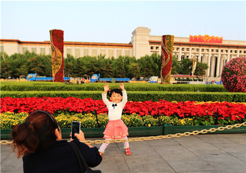 天安門廣場，一位小朋友在已經佈置完畢的綠地花卉前留影。