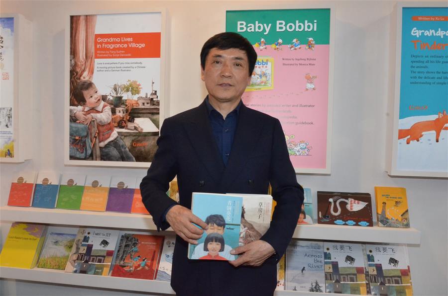 Chinese writer Cao Wenxuan poses with his works at the Bologna Children