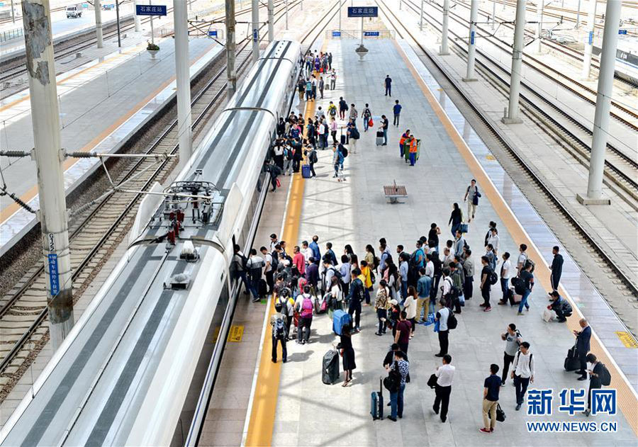 Passengers get on a bullet train at Shijiazhuang Rail Station, north China