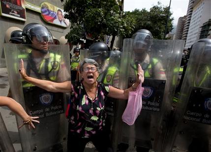 A demonstrator is blocked by Bolivarian National police during an anti-government march to the headquarters of the national electoral body, CNE, in Caracas, Venezuela, Wednesday, May 18, 2016. Opposition protesters were blocked from reaching the CNE as they demand the government allow it to pursue a recall referendum against Venezuela