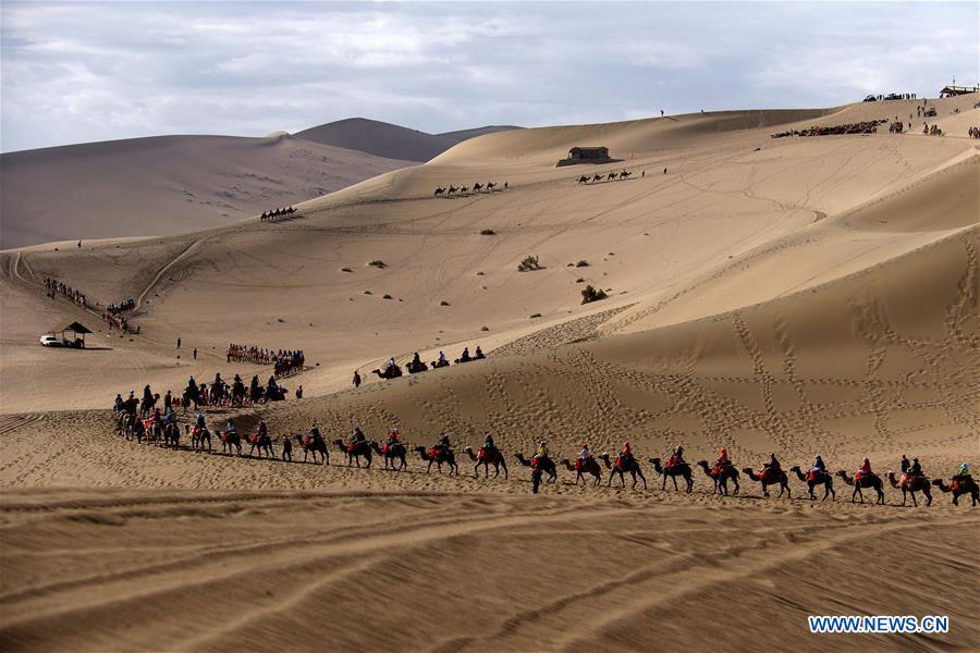 Des touristes visitent le le site de la source du Croissant de lune et des dunes Mingsha, à Dunhuang, dans la province chinoise du Gansu (nord-ouest), le 10 juin 2016. Les Chinois ont joui des vacances de trois jours de la Fête des bateaux-dragons de différentes façons. (Xinhua/Zhang Xiaoliang)