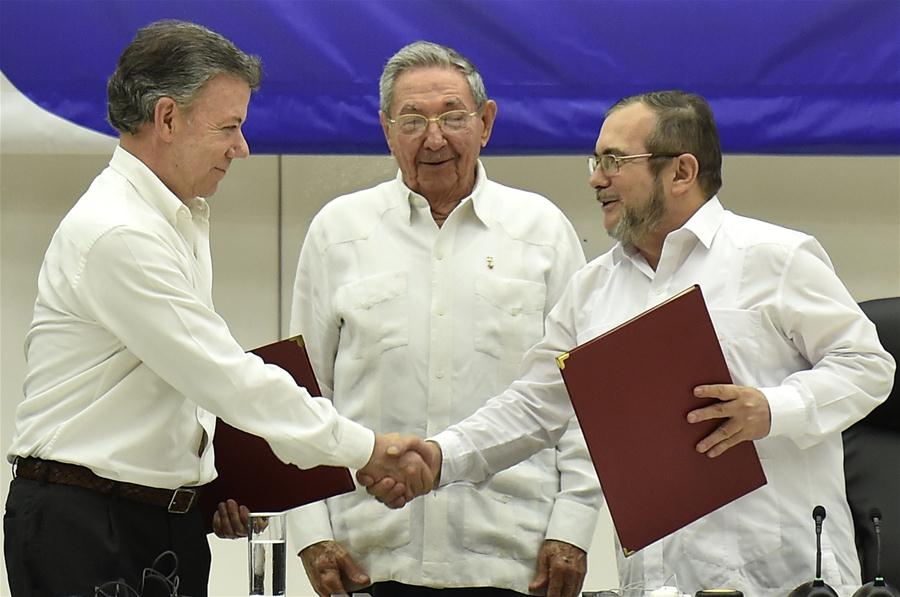 Colombian President Juan Manuel Santos (L) shakes hands with Timoleon Jimenez (R), the top leader of the Revolutionary Armed Forces of Colombia (FARC), next to Cuban President Raul Castro, in the signing ceremony of a historic ceasefire agreement between the Colombian government and the FARC, in Havana, capital of Cuba, on June 23, 2016. (Xinhua/Str) 