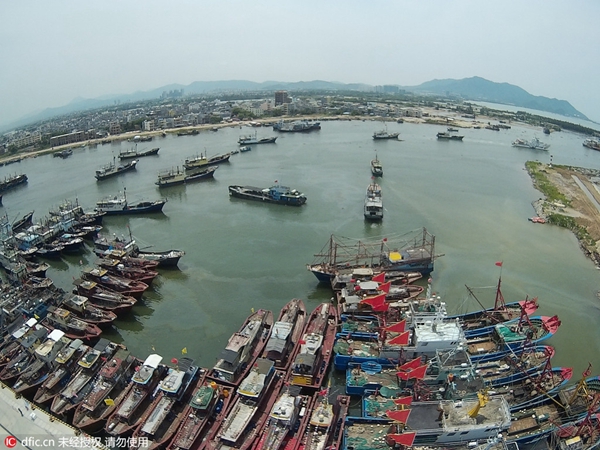 More than 300 fishing vessels flying red flags leave the port at noon for nearby South China Sea fishing ground.