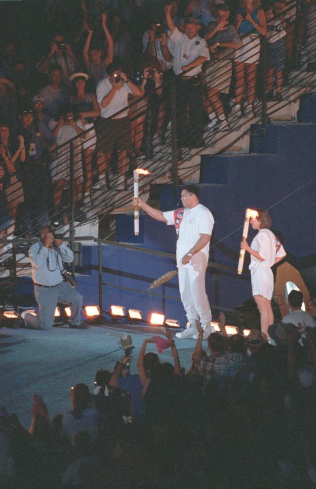 圖為1996年7月19日，前世界重量級拳王阿裏（中）點燃第26屆亞特蘭大奧運會聖火