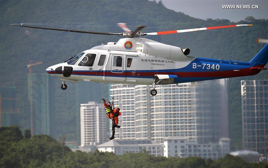 A helicopter demonstrates how to rescue people falling into water during an emergency rescue drill held at the sea area near Fenghuang island in Sanya, south China