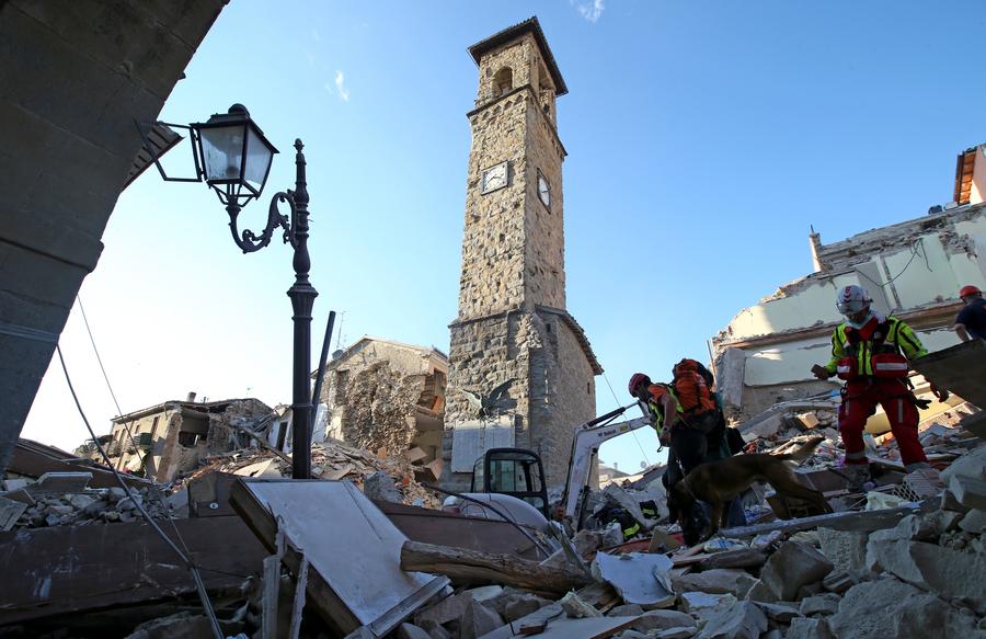 Rescuers walk past the bell tower with the clock showing the time of the earthquake in Amatrice, central Italy, August 24, 2016. [Photo/Agencies]