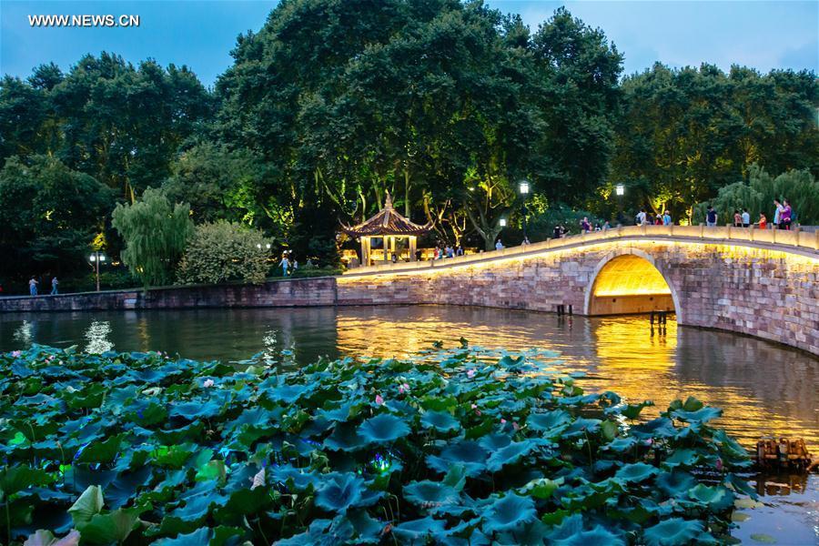 Tourists walk on the Xiling Bridge across the West Lake in Hangzhou, capital of east China