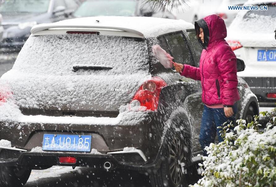 A citizen cleans snow on her car in Changchun, northeast China