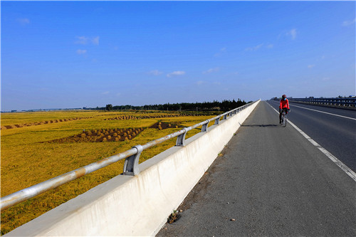 一名騎行愛好者行駛在五常市杜家鎮境內的高速公路上。（圖  吳胡荼）