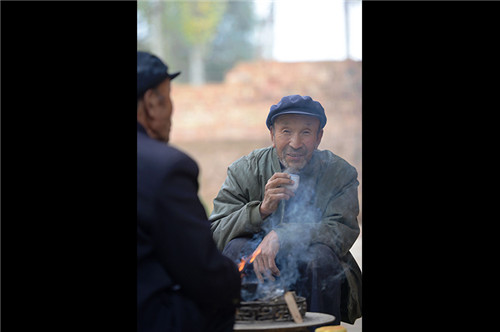 許志強（右）在自家小院裏與哥哥許志剛圍著火爐喝罐罐茶聊天