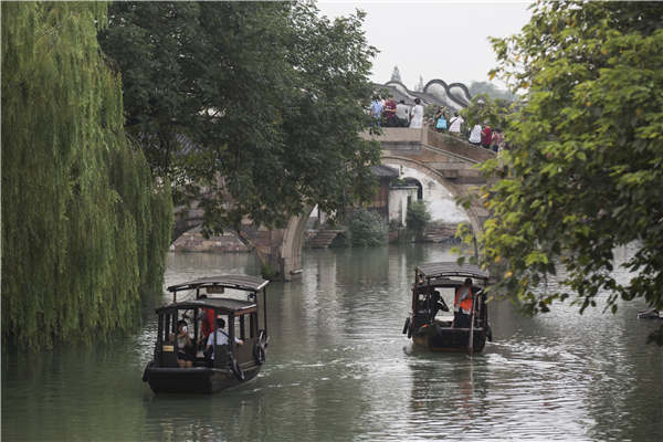 Crisscrossing waterways are now the biggest draw for visitors to Wuzhen, Zhejiang province. Visitors stroll along the banks or hop aboard boats to take in the views. [Photo by Shi Kuihua/For China Daily]