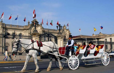 這是2008年11月15日遊人乘坐馬車經過秘魯首都利馬老城總統府。新華社記者 王晗 攝