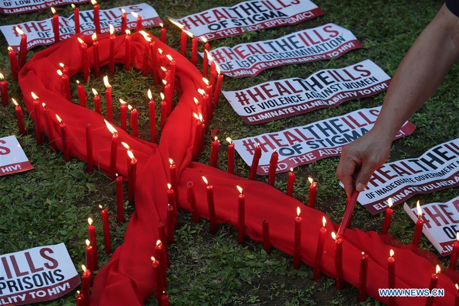 A man lights candles on a red ribbon-shaped cloth in observance of the World AIDS Day in Quezon City, the Philippines, Dec. 1, 2016. People around the world are observing the World AIDS Day to raise awareness and prevention on HIV/AIDS. (Xinhua/Rouelle Umali)