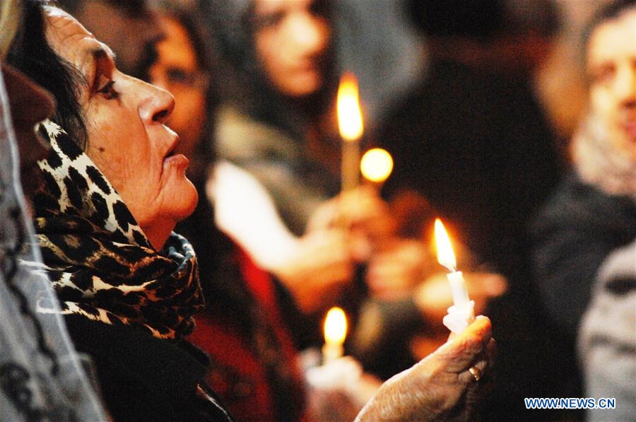  A woman holds a candle during the Christmas Mass in Bartella town, about 20 KM east of Mosul city in northern Iraq, on Dec. 24, 2016. About one hundred people gathered in Bartella town in northern Iraq on Saturday to attend the Christmas Mass. (Xinhua/Khalil Dawood) 