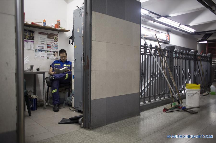 Imagen del 10 de diciembre de 2016 del escritor argentino, Enrique "Kike" Ferrari, leyendo un libro durante su tiempo de descanso en la estación Pasteur-AMIA de la línea B del Metro donde trabaja en el turno nocturno de limpieza, en Buenos Aires, Argentina. Ferrari, quien trabaja de 11 de la noche a cinco de la mañana en la estación, transmite su pasión por la escritura, por la que ha sido premiado y traducido al francés y el italiano, y la forma en que conjuga esa actividad con la limpieza. Escritor de novelas y cuentos del género negro premiado en Argentina, España, Francia y Cuba, admite que trabajar de noche le "dificultó la estructura". Me gusta escribir de mañana. Me despertaba temprano los sábados y domingos para escribir hasta el mediodía. Pero con la rutina de trabajar en la madrugada, el formato de escritura debió cambiar. Ferrari rescató las posibilidades que abre el hecho de estar despierto cuando la mayoría de los "porteños" duerme. "Así como molesta el horario, acompaña un poco la soledad, el silencio. Estar en un lugar en el que no hay nadie más que nosotros, haciendo un trabajo que requiere esfuerzo físico, me sirve", puntualizó. (Xinhua/Martín Zabala) (mz)