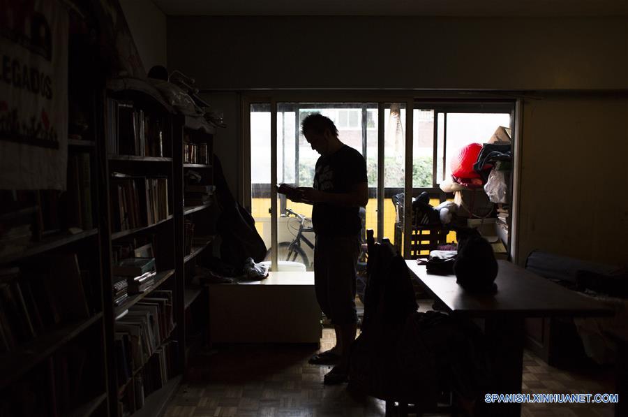 Imagen del 4 de enero de 2017 del escritor argentino, Enrique "Kike" Ferrari, consultando un libro de su biblioteca en su departamento, en Buenos Aires, Argentina. Ferrari, quien trabaja de 11 de la noche a cinco de la mañana en la estación, transmite su pasión por la escritura, por la que ha sido premiado y traducido al francés y el italiano, y la forma en que conjuga esa actividad con la limpieza. Escritor de novelas y cuentos del género negro premiado en Argentina, España, Francia y Cuba, admite que trabajar de noche le "dificultó la estructura". Me gusta escribir de mañana. Me despertaba temprano los sábados y domingos para escribir hasta el mediodía. Pero con la rutina de trabajar en la madrugada, el formato de escritura debió cambiar. Ferrari rescató las posibilidades que abre el hecho de estar despierto cuando la mayoría de los "porteños" duerme. "Así como molesta el horario, acompaña un poco la soledad, el silencio. Estar en un lugar en el que no hay nadie más que nosotros, haciendo un trabajo que requiere esfuerzo físico, me sirve", puntualizó. (Xinhua/Martín Zabala)