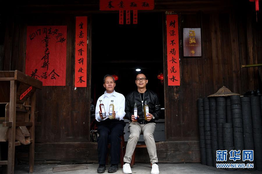 Huang Baofeng(izquierdo) y Yang Tianji mostran los productos del vino de arroz, el 11 de enero de 2017. 