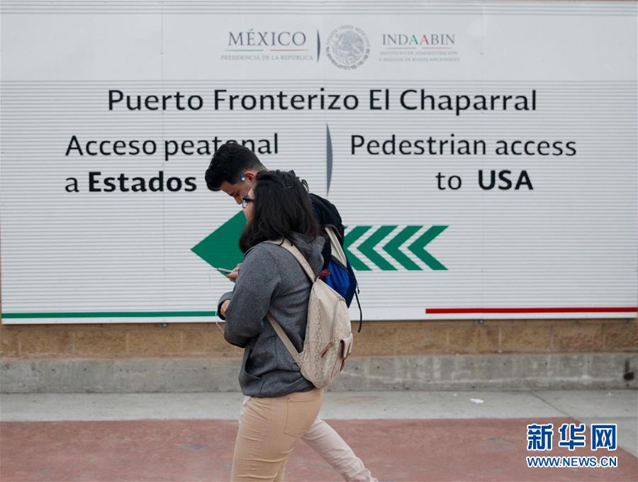 Jaime y su compañero pasan por una tabla de anuncio que se alza en el acceso peatonal a Estados Unidos