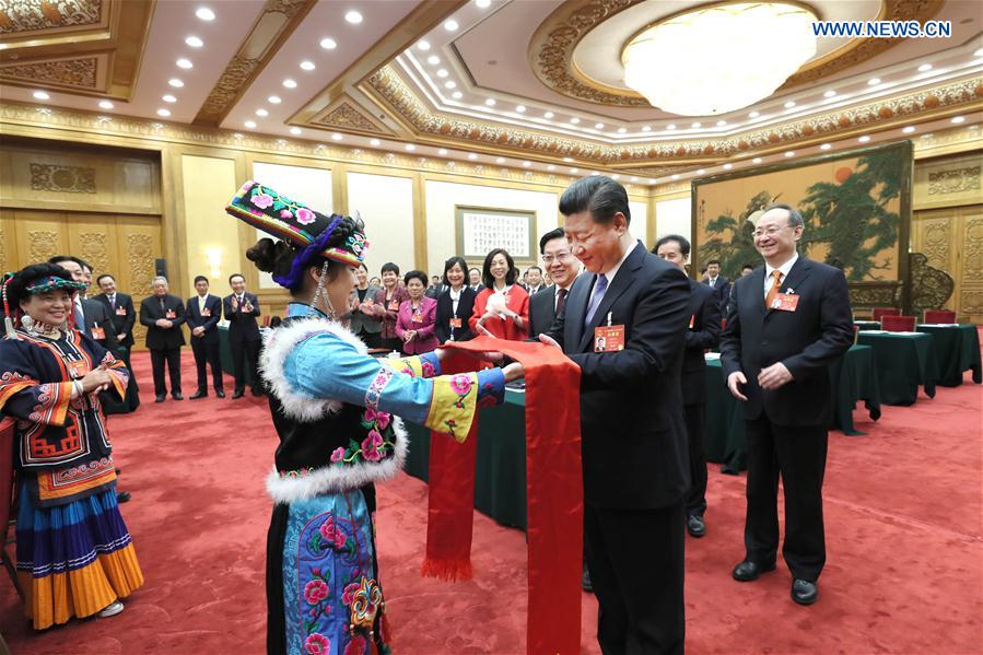 Chinese President Xi Jinping receives Qianghong, a ceremonial silk scarf regarded as a token of respect, from a deputy of Qiang ethnic group when joining a panel discussion with deputies to the 12th National People