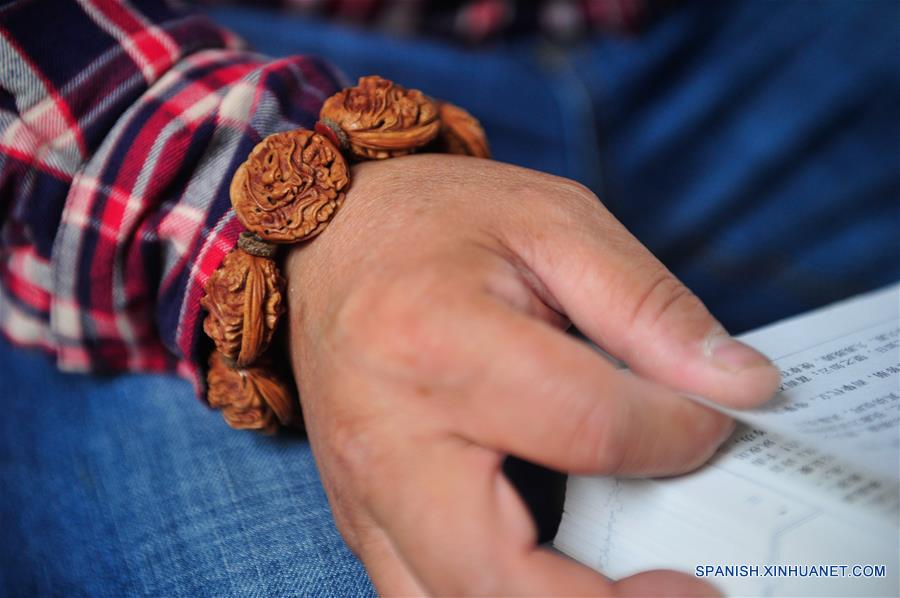 ANHUI, marzo 20, 2017 (Xinhua) -- El artista Ma Yongbing utiliza una pulsera de figuras talladas en huesos de duraznos en Xuancheng, provincia de Anhui, en el este de China, el 20 de marzo de 2017. El los últimos 25 años, Ma Yongbing, ha creado más de un millar de piezas de esculturas en huesos de durazno. Las creaciones de Ma destacan principalmente las historias chinas tradicionales, arquitecturas, paisajes, entre otros. (Xinhua/Meng Dingbo)