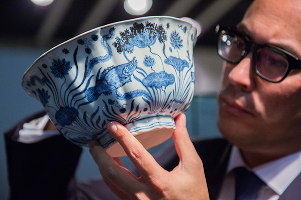 A staff holds the Xuande Bowl. [Photo provided to China Daily]