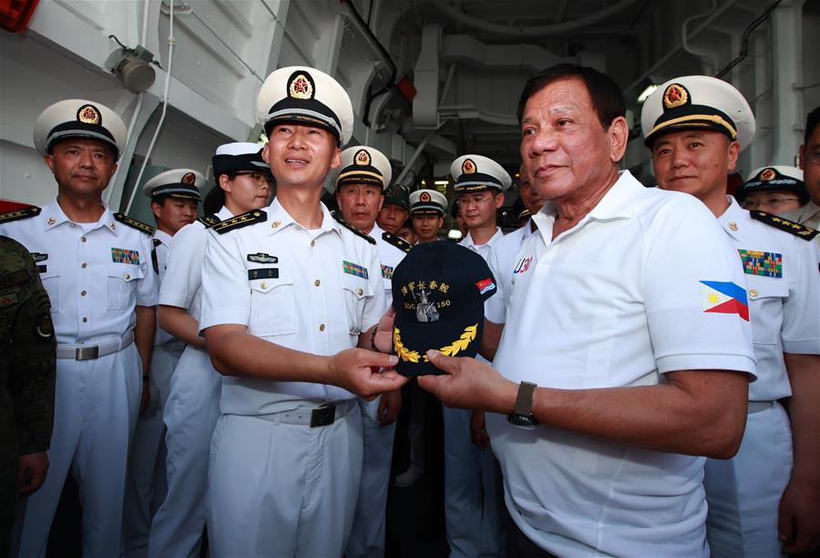 Philippine President Rodrigo Duterte (R, front) receives a hat from Hu Jie (L, front), captain of China