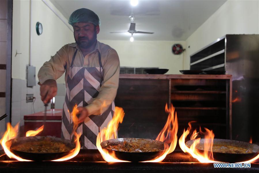 A chef stews mutton in an iron pot at a stall along a food street in Pakistan