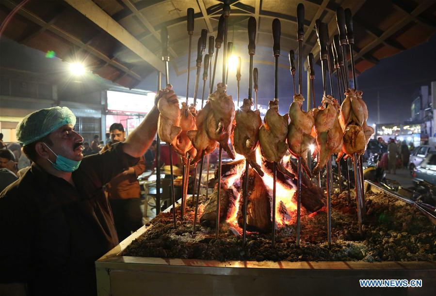 A chef roasts chicken at a stall along a food street in Pakistan