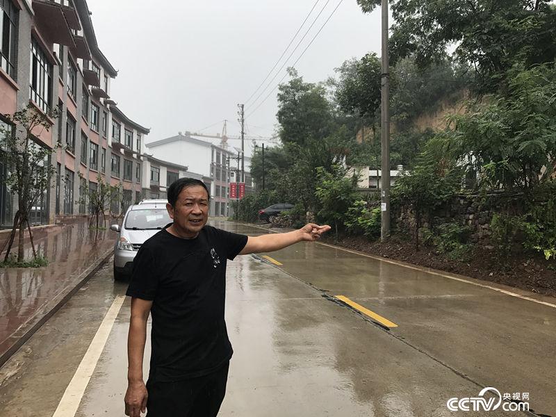 52歲趙書進手指著還沒有開發的舊房子，在他身後是自己即將開業的商鋪。（王莉莉 攝）