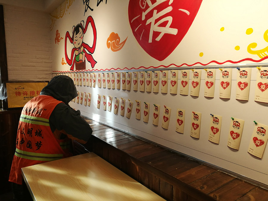  Every sanitation worker has to write his name before he gets the free meal. [Photo provided to chinadaily.com.cn] 