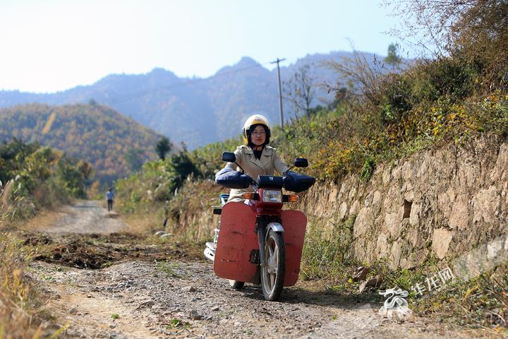 嚴克美騎著男士摩托走訪村民。記者-李文科攝.jpg